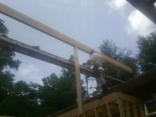 Carpenter setting a ridge beam over a new addition frame in Muskego
