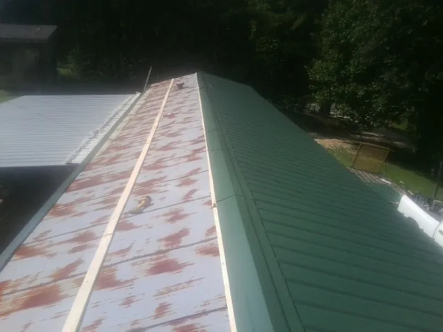 Old rusted panels beside newly installed green metal roofing — Wind Damage Roof Repair by Roofing Brothers in Muskego