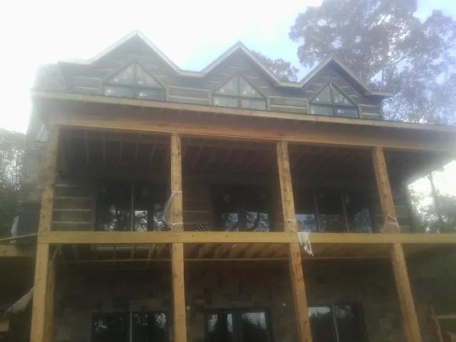 Dormers and porch framing on a large log home under construction — Roof Coating work by our crew in Muskego