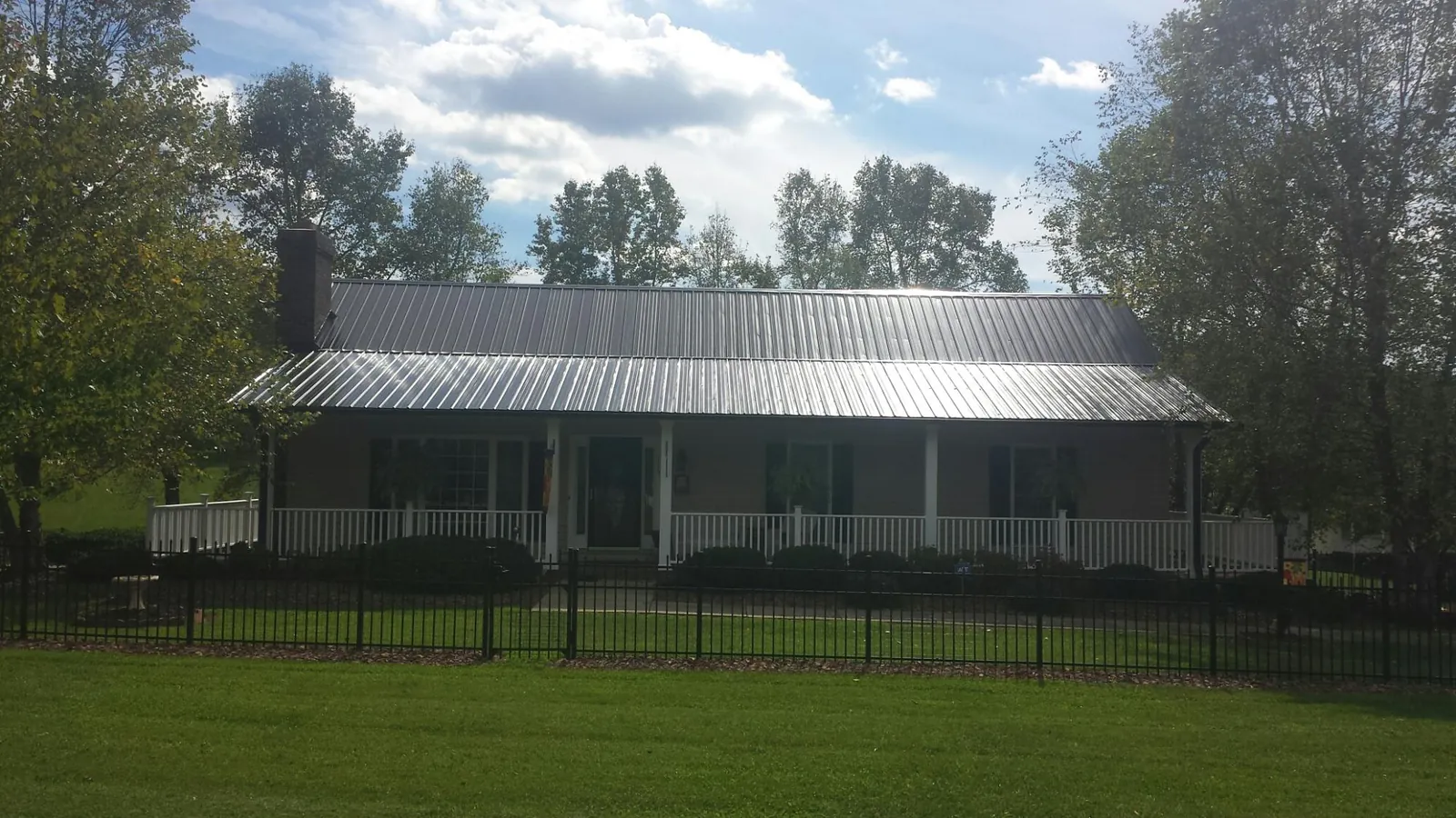 Gray metal roof on a brick ranch with a full width front porch — Gutter Guard Installation work by our crew in Muskego
