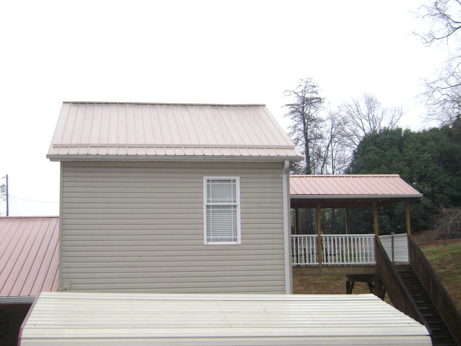 Tan metal roofs on a two story addition and attached porch, from a Roof Replacement job in Muskego