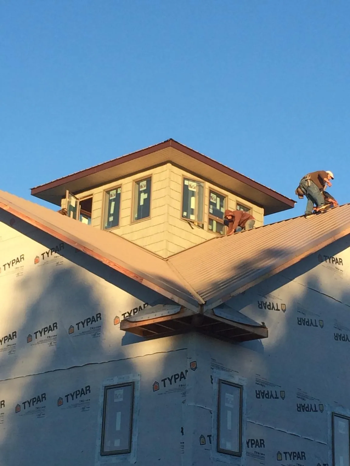 Roofers working around a rooftop cupola on a new metal roof at sunset — Roof Waterproofing in Muskego by Roofing Brothers